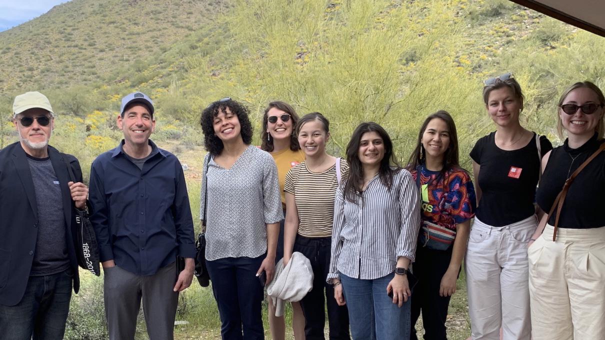 Students and faculty pose for a photo in front of a small, green mountain on-site in Phoenix, Arizona.